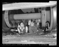 Eleanor Maldonado and Jenny Rodriguez, beneath train doing maintenance work at Los Angeles Union Station, circa 1945