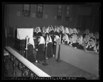 Young girls kneeling around Cardinal Rodrigue Villeneuve's coffin during his Requiem Mass at Ramona Covent in 1947
