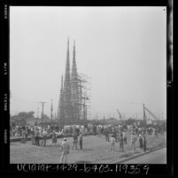 Watts Towers, surrounded by scaffolding, undergoes pressure testing as people watch in Los Angeles, Calif., 1959