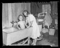 Little girl being bathed by her mother in laundry tub at Brookside Emergency Housing Project, Pasadena, Calif., 1948