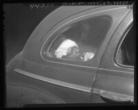 Wounded suspect, Minton R. Scott in police car after being shot by officers in Los Angeles, Calif., 1947