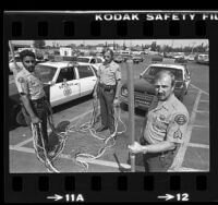 Three Los Angeles County Sheriff deputies displaying net used to subdue suspects, 1980