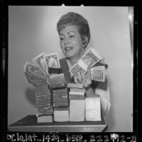 Bank teller, Mrs. Joe Melton holding amount of money that the average San Fernando Valley, Calif. family made in 1963