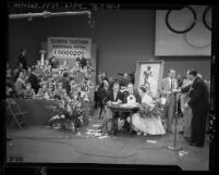 Bing Crosby, Bob Hope and Dorothy Lamour surrounded by band and telephone operators at telethon for 1952 Olympic Games