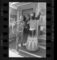 Title =Los Angeles-based comedian, Pee Wee Herman (Paul Reubens) posing with stuff monkey on Melrose Ave. in Los Angeles, Calif., 1984