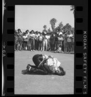 Escape artist Tim Eric performing in chains and straitjacket as crowd looks on in Venice Beach, Calif., 1984
