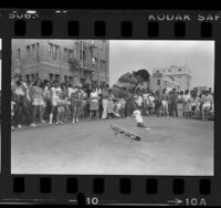 Primo Desidero performing freestyle skateboarding as crowd looks on in Venice Beach, Calif., 1984