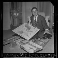 Randolph P. Barton, vice president of Parker Bros., sitting on floor with collection of board games, 1964