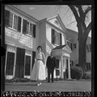Woman modeling gown out front of house with Clairbourn School's headmaster Holford, San Gabriel, Calif., 1965