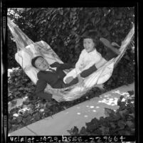 Vietnam war orphans Minh Son and Kim Phuong swinging in hammock at home of their adoptive parents in Northridge, Calif., 1965