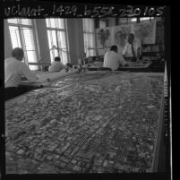 Men working at drafting tables next to scale model of Los Angeles in Los Angeles City Planning Department, 1965