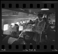 Flight attendant handing newspaper with headline "Planes Fly Again Machinists' Vote Ends Strike," in plane passengers, 1966
