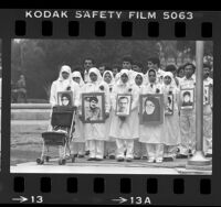 Arab men and women, dressed in all white, wearing pictures of objectors during demonstration against Iran's Ruhollah Khomeini in Los Angeles, 1985