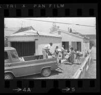 Reverend John Bradford helping Hazel Evans and family move into their home in Watts, Calif., 1968