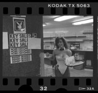 Playboy Bunny in kitchen beside employee bulletin board at Playboy Club in Los Angeles, Calif., 1986