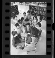 Library aide reading book in Spanish to group of Mexican American children at East Los Angeles County Library, 1970