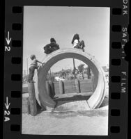 Children playing on cement drain conduit at Pico-Union Community park in Los Angeles, Calif., 1971