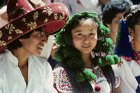 Guelaguetza[?], dancers close-up of man in red hat and woman in green headgear [view 2], 1982