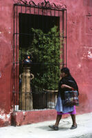 Oaxaca, woman walking by barred window, 1982 or 1985