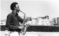 Lewis Jordan playing saxophone on a rooftop, 1978 [descriptive]