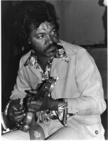 Evans Walker holding his guitar, 1977 [descriptive]