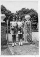 Two girls at front gate of house
