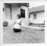 Little girl playing with beach ball in front of house