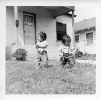 Two babies standing in front of house