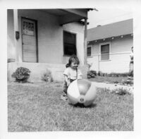 Little girl playing with beach ball in front of house