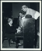 Joan Fontaine playing the piano for William Dieterle and Hal Wallis between scenes on September Affair
