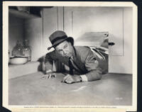 Dick Powell tries to wriggle through the doggy door in a scene from You Never Can Tell