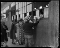 Unidentified men and women receive sacks of flour at a county food exchange program, Los Angeles, 1930s