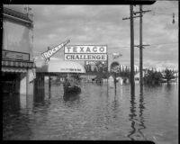 Three men ride a boat across flood waters, Long Beach, circa 1930s