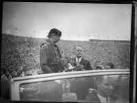 First Lady Eleanor Roosevelt stands in car with welcome bouquet, Los Angeles Memorial Coliseum, October 1, 1935