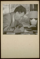 Aldous Huxley portrait, at desk, looking down, holding a pen, in writing studio, Llano CA