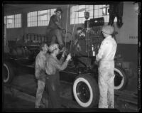 Men at work completing an automobile at the Los Angeles Studebaker assembly plant in Vernon, CA.  Circa January 2, 1936.