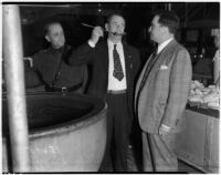 Sam Williams eating from a large spoon with Police Captain Clement Peoples and Sheriff Eugene Biscailuz at the Los Angeles County Jail