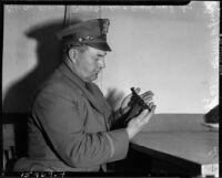 Robert W. Trowbridge examines the handgun used by Paul A. Wright to fatally shoot his wife and best friend, Glendale, November 10, 1937