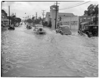 Automobiles drive through flooded streets caused by heavy rainstorms, January 1940