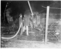 Fire fighters hosing down the former site of the Golden State Fireworks and Display Co. plant after an explosion, February 1940