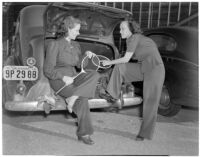 Mrs. Kenneth Holmes and Mrs. Gwynn Fielding with tennis rackets by an automobile, Los Angeles, circa 1940