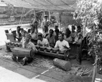 Male musicians playing the gamelan with children watching