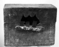 Photo of a wooden crate with the pattern cut in the center, embellished with three metal teeth at the base of the pattern