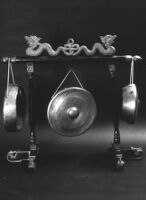 Three gongs suspended from a frame adorned with two bronze serpents