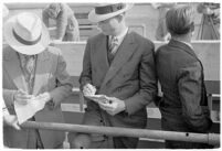 Sports officials writing down times at a track meet between UCLA and USC, Los Angeles, 1937