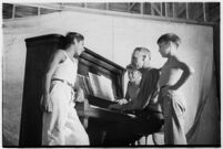 Boys gathered around piano and pianist, taking part in a free summer camp organized by Los Angeles Sheriff Eugene Biscailuz.  Circa July 1937.
