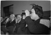 Female spectator uses binoculars to view court proceedings during the trial of Police Captain Earle E. Kynette, Los Angeles, 1938