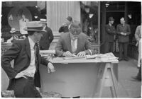 Nile Shrine member folding flyers on the street, Los Angeles, 1938