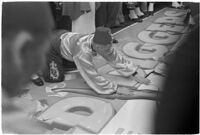 Member of the Mystic Shrine attending to a sign for the Durbar festival, Los Angeles, 1937