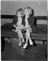 Sisters Kathleen and Jacqueline Milroy sitting together on a bench, Los Angeles, 1940
